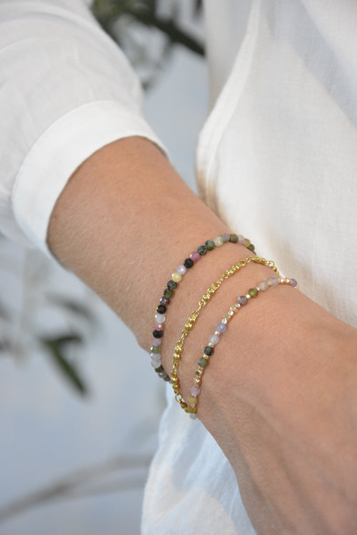 Dreiteiliges Armbandset aus Turmalinperlen und goldenen Edelstahlperlen. Das Armbandset wird getragen und man sieht den Arm und eine weiße Bluse im Hintergrund. 